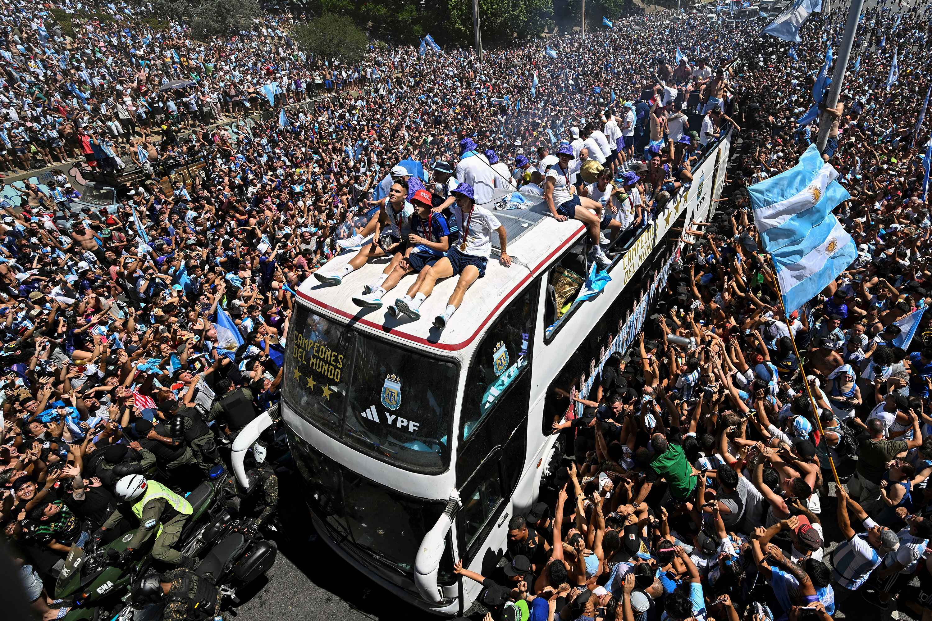 Los fanáticos de Argentina animan mientras el equipo desfila a bordo de un autobús después de ganar el torneo de la Copa Mundial de Qatar 2022 en Buenos Aires, Argentina, el 20 de diciembre de 2022. - Se espera que millones de fanáticos exultantes animen a sus héroes como los ganadores de la Copa Mundial de Argentina liderados por El capitán Lionel Messi comenzó su desfile de autobuses descubiertos de la capital Buenos Aires el martes luego de su sensacional victoria sobre Francia. (Foto por Luis ROBAYO / AFP).