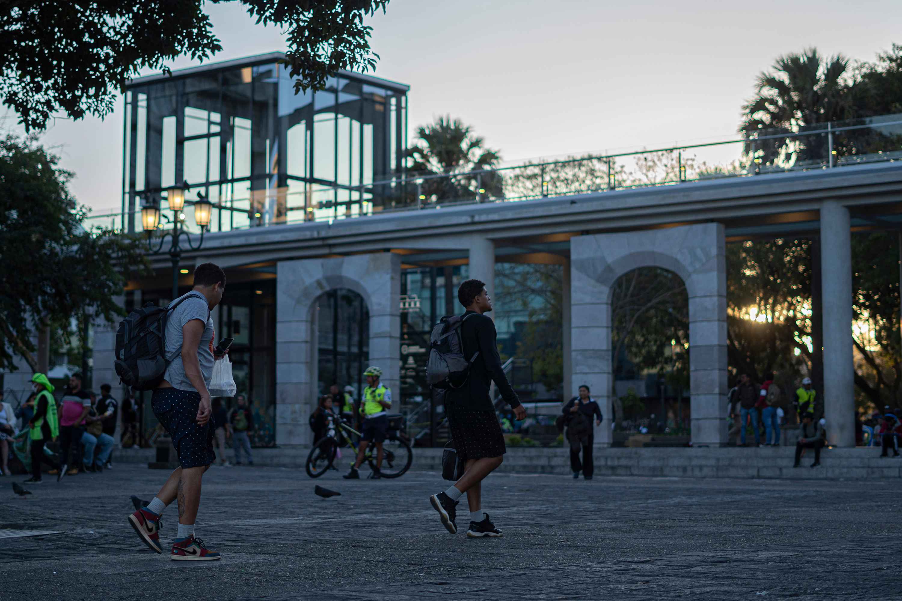 John (left) and Yoiner, 23 and 20 years old, respectively, cut through Constitution Plaza in the center of Guatemala City on their way to their hotel after a long day of asking for money for eight hours. Childhood friends from the heart of Caracas, one left the country in 2017 and the other in 2022. They reunited on their way to the United States. Photo: Víctor Peña/El Faro