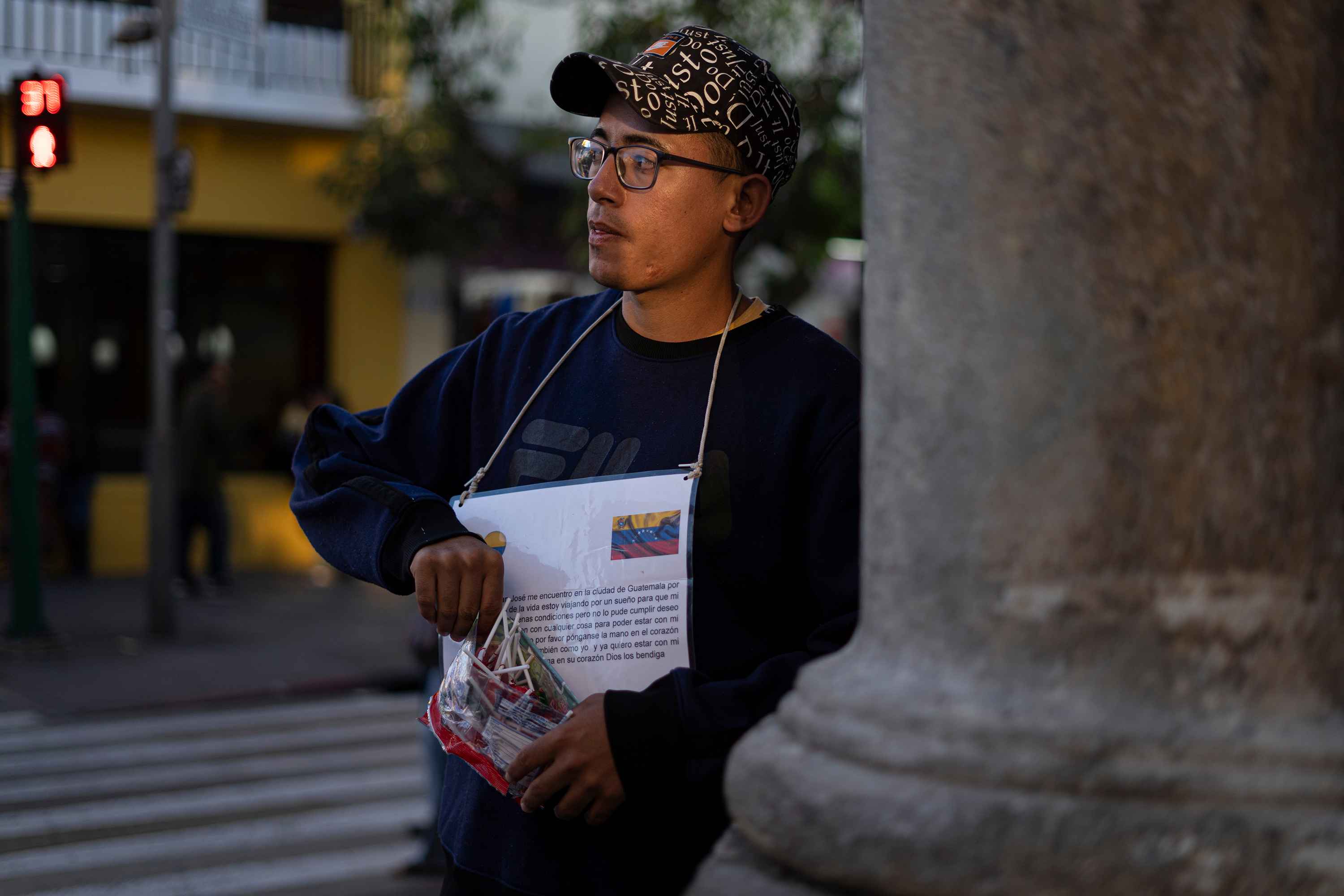 Juan sells candies on Sixth Avenue in front of the San Martín bakery. It's his regular corner where he scrapes together change for his hotel and meals with a bag of candies and a sign identifying him as a Venezuelan migrant stuck in Guatemala City. Photo: Víctor Peña/El Faro