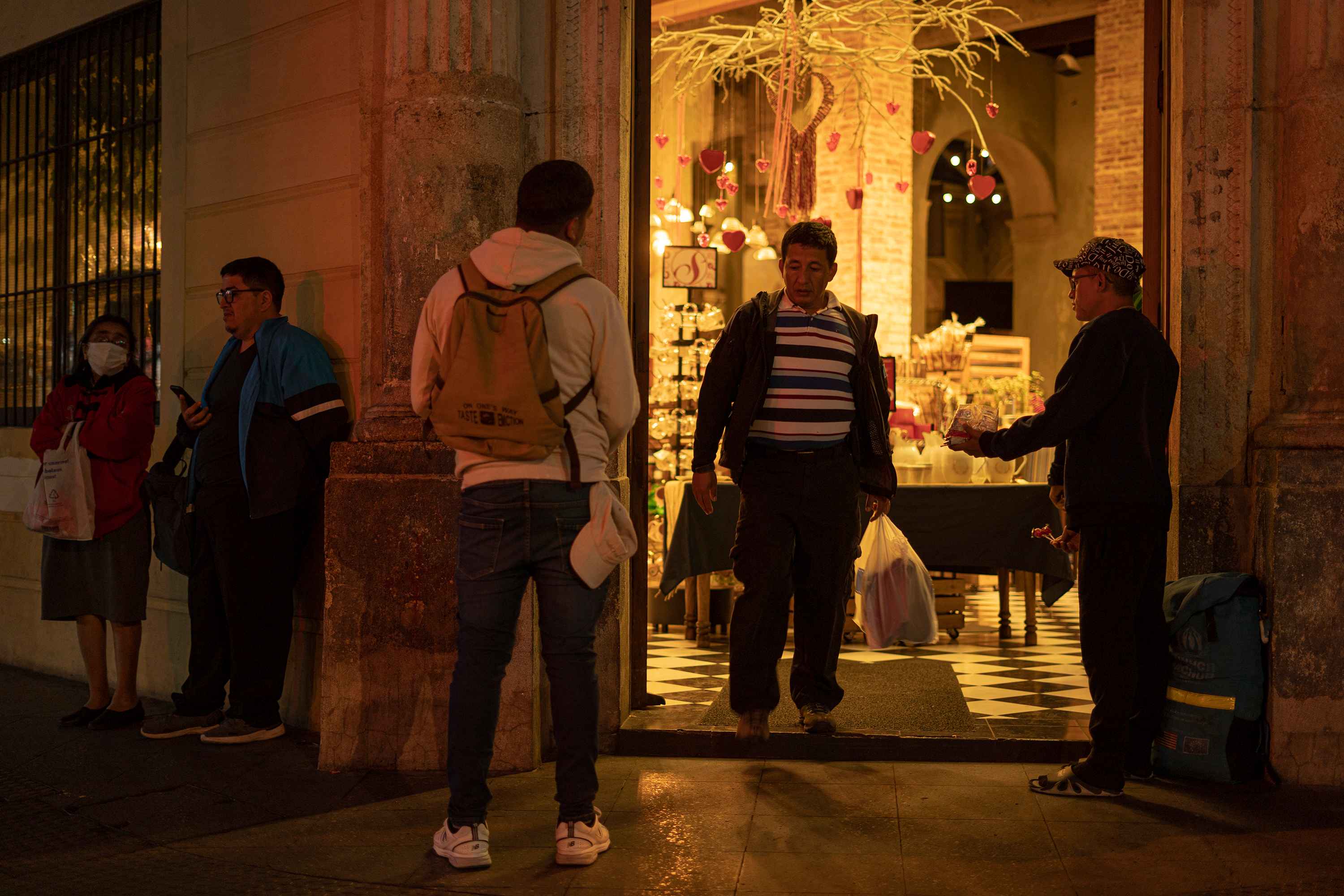 Leonardo Caguana and Juan ask for money and sell candies in front of the San Martín bakery on Sixth Avenue. Venezuelan migrants have become a daily presence on this street corner. Photo: Víctor Peña/El Faro