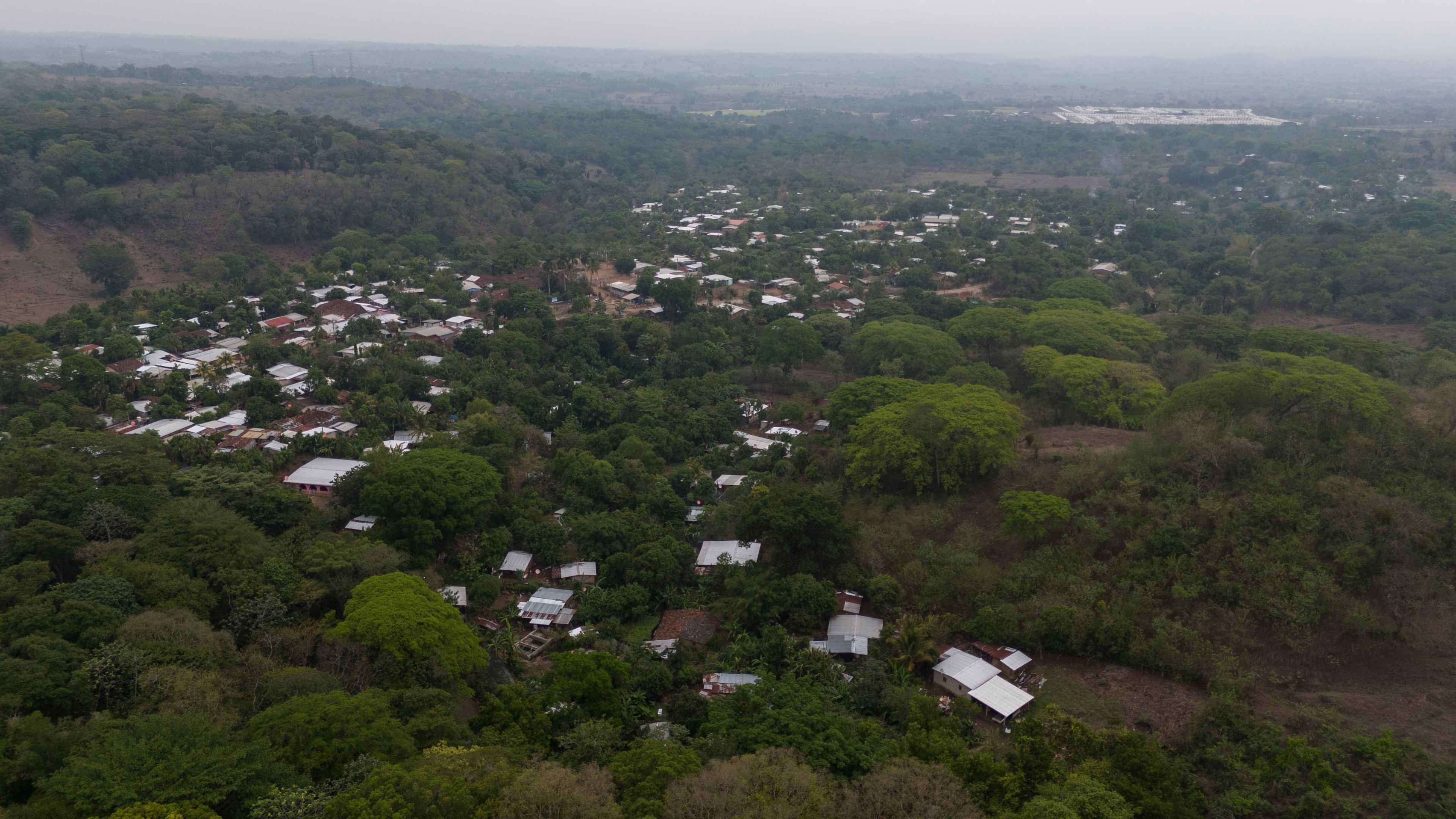 En enero de 2022, los habitantes de la Hacienda La Labor, en el departamento de Ahuachapán, se organizaron para protestar contra Fénix, una inmobiliaria que iniciaba un proyecto de construcción de 1,764 casas llamado Eco Terra Hacienda. La empresa también perforó un pozo para abastecer el proyecto, pese a no tener los permisos ambientales. La perforación amenazaba el acceso al agua de la comunidad y afectaba a más de 500 familias que residen en ese sector. Los habitantes protestaron para detener la perforación, pero tres de sus líderes fueron capturados por invadir la propiedad privada. Estos líderes fueron los primeros encarcelados durante la gestión Bukele por defender su agua. Dos años después, casi todo sigue igual, dicen algunos habitantes. La construcción ha avanzado, como se ve al fondo en la imagen, y ya nadie protesta por el pozo. Y, aunque todos los miembros de la comunidad fueron absueltos de los cargos, Fénix continúa con el litigio judicial. Foto de El Faro: Víctor Peña.