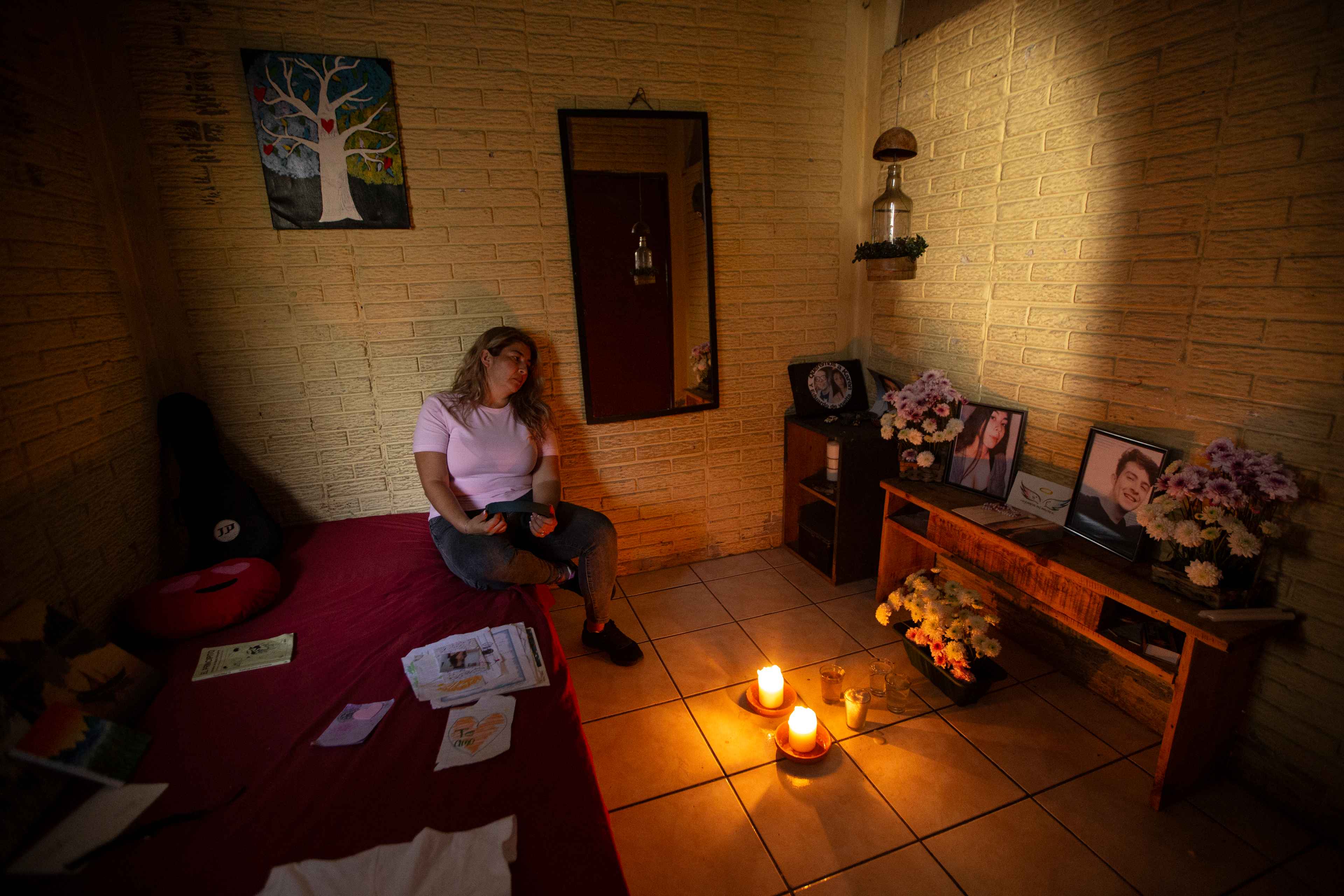 El 18 de septiembre de 2021, los hijos de Ivette, Karen y Eduardo Guerrero, fueron secuestrados en la colonia Quezaltepec, en el municipio de Santa Tecla. Ella emprendió una búsqueda exhaustiva de 98 días, hasta que sus cuerpos fueron encontrados el 23 de diciembre en un cementerio clandestino, en el municipio de Nuevo Cuscatlán.  El caso tuvo alcances mediáticos altos, que diferían de la campaña gubernamental del "Plan Control Territorial" y el descenso de la violencia. "Todavía sufro esas consecuencias, aunque ya no esté en el país. Los funcionarios no calculan el daño que ocasionan. Para muchos, mis hijos murieron por ser pandilleros y narcotraficantes, porque ese es el mensaje que dio el gobierno y el ministro Gustavo Villatoro”, dice. Ivett también asegura que la involucraron en una coyuntura política por el impacto de su caso. Por esa razón se negó a seguir con un abogado defensor. Su proceso judicial ahora depende de lo que la Fiscalía le informe, que muchas veces es poco o nada, debido a la reserva total del caso. “Desde que encontré a mis hijos el Gobierno me acorraló a partir de las declaraciones de Gustavo Villatoro. Yo no estaba segura en ningún lugar. Sentí que algo me podía pasar, y no desde el lado de los pandilleros que controlaban mi colonia, sino de ataques desde el gobierno por ensuciar su imagen. Ahora, al menos ya no estoy en zozobra. Venirme para acá no me arregla la vida porque aquí también es complicado sobrevivir". Ivette Toledo huyó de El Salvador hace algunos meses y prefiere no revelar el lugar donde se encuentra. Ahora trabaja en el área de cocina de un hospital público, en el país que le ha ofrecido un refugio humanitario. En la imagen, Ivette permanece en la habitación que pertenecía a sus hijos, donde ella colocó un altar para recordarlos. Foto de El Faro: Víctor Peña.