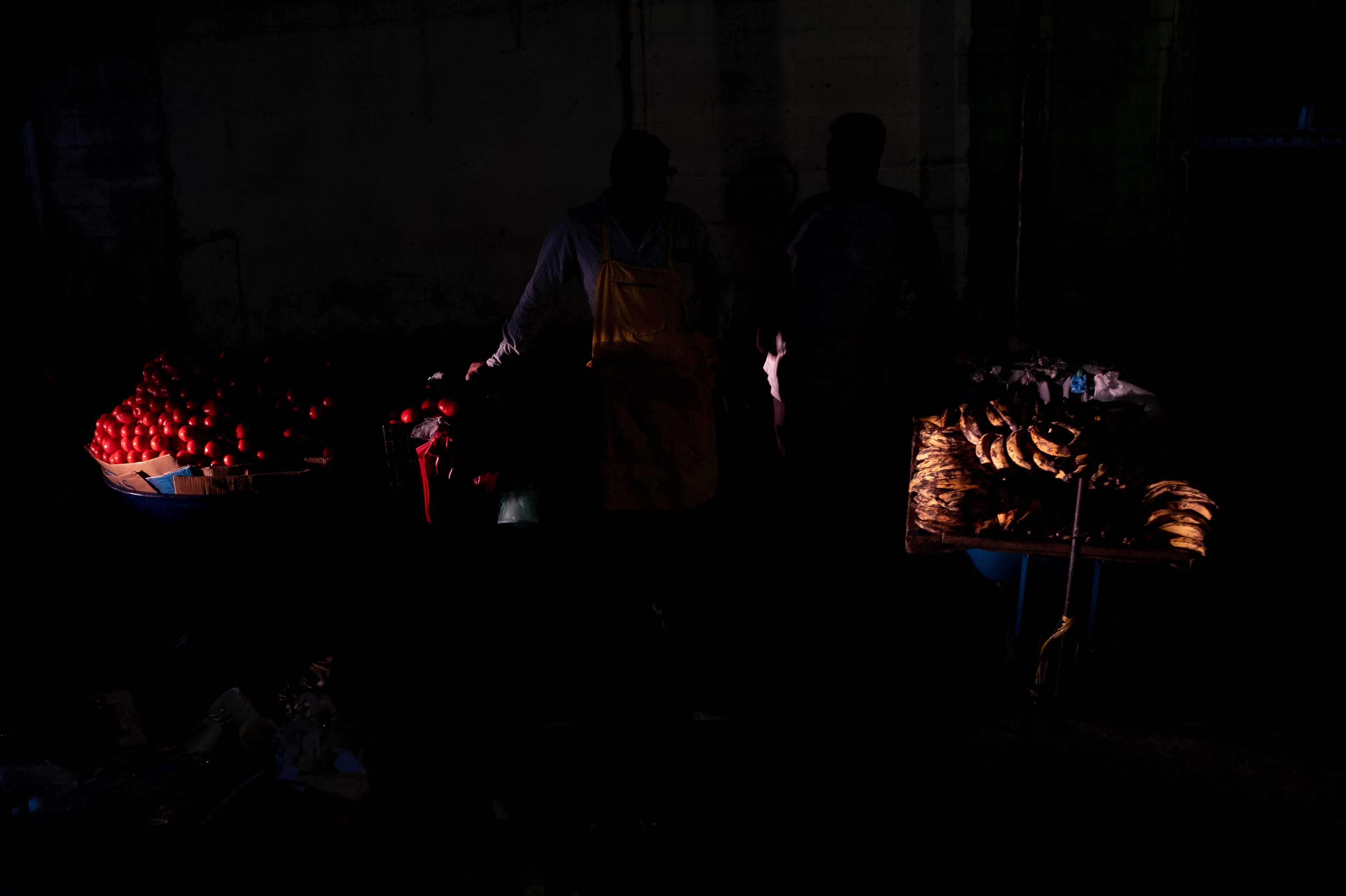 Saúl y Rigoberto descansan después de alejarse de los agentes del CAM, a cuadra y media de la Binaes. En una zona en oscuridad, fuera de las cuadras remodeladas de El Centro, apenas eran iluminados por los vehículos que transitaban sobre la octava calle poniente. Ellos no viven en la zona del Centro Histórico pero pagan $50 mensuales por una bodega para guardar el producto que venden. "La zona iluminada está bien bonita, pero cada vez se nos hace más jodido acercarnos para intentar vender", dijo Rigoberto. "Quizás un día ya ni vamos a poder vender aquí", replicó Saúl. Foto de El Faro: Carlos Barrera