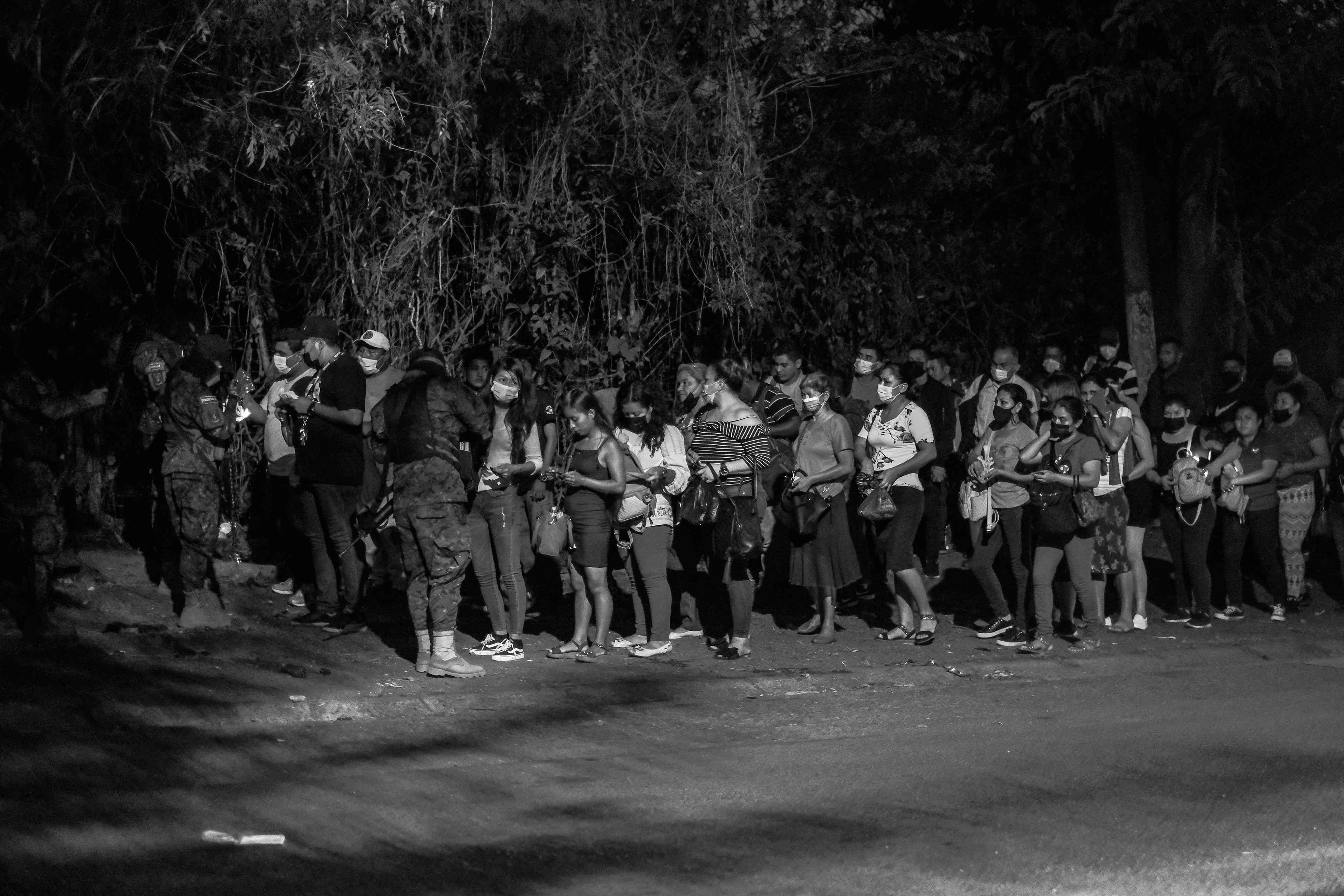La gente hace fila para mostrar sus identificaciones a la policía en un puesto de control en Distrito Italia, San Salvador, durante los primeros días del estado de excepción en abril de 2022.